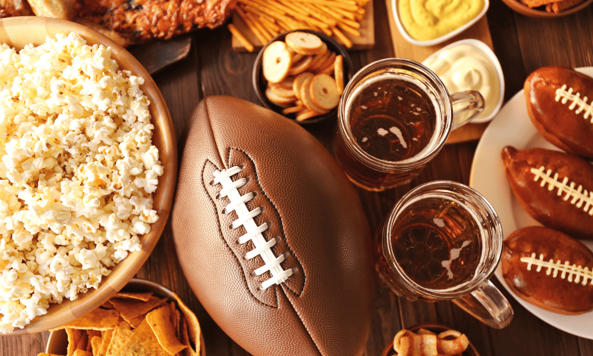 an America football, beer, popcorn and snacks