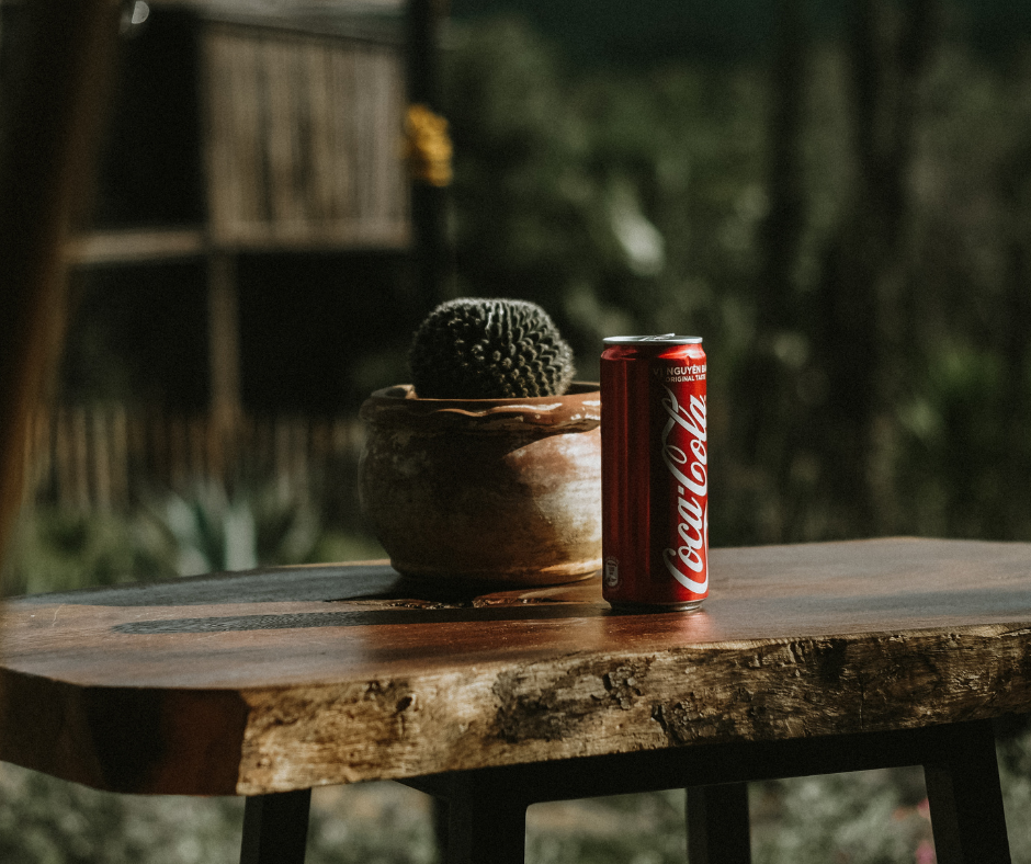 Capital Letters in English - Coca Cola on a table next to a cactus plant